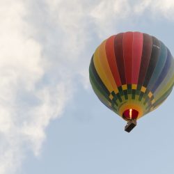 Colorful hot air balloon soaring amidst clouds in Valladolid, Spain.
